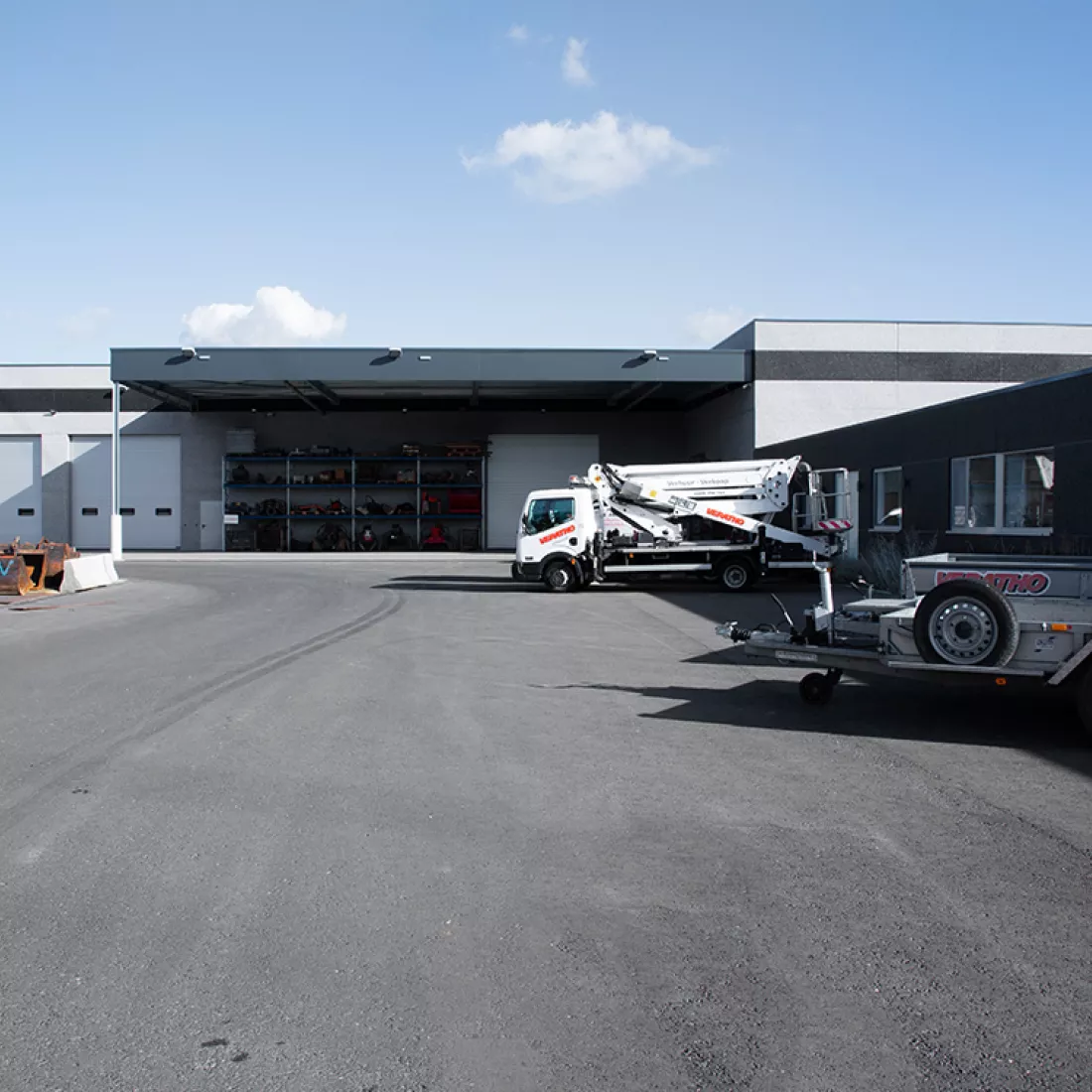 Vooraanzicht magazijn Veratho. Het gebouw is grijs met zwart. Het gebouw is gemaakt uit staal. Het gebouw heeft een ook zwart afdak en witte poorten.
