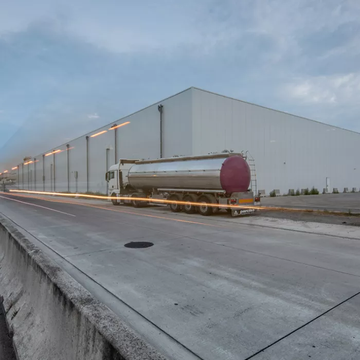 Zijaanzicht Citrosuco diepvriesloods. Het gebouw is wit. De afbeelding is genomen vanaf de overkant van de straat.