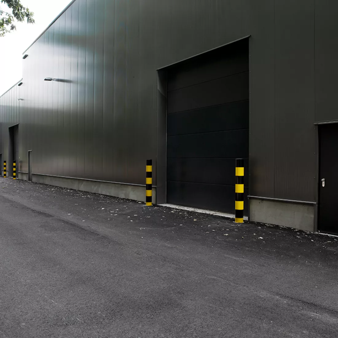 Zijaanzicht bedrijfsunits Immo Bolckmans Geelseweg. Het is een gebouw gemaakt uit staal. Het is donkergrijs en bevat zwarte poorten en deuren.