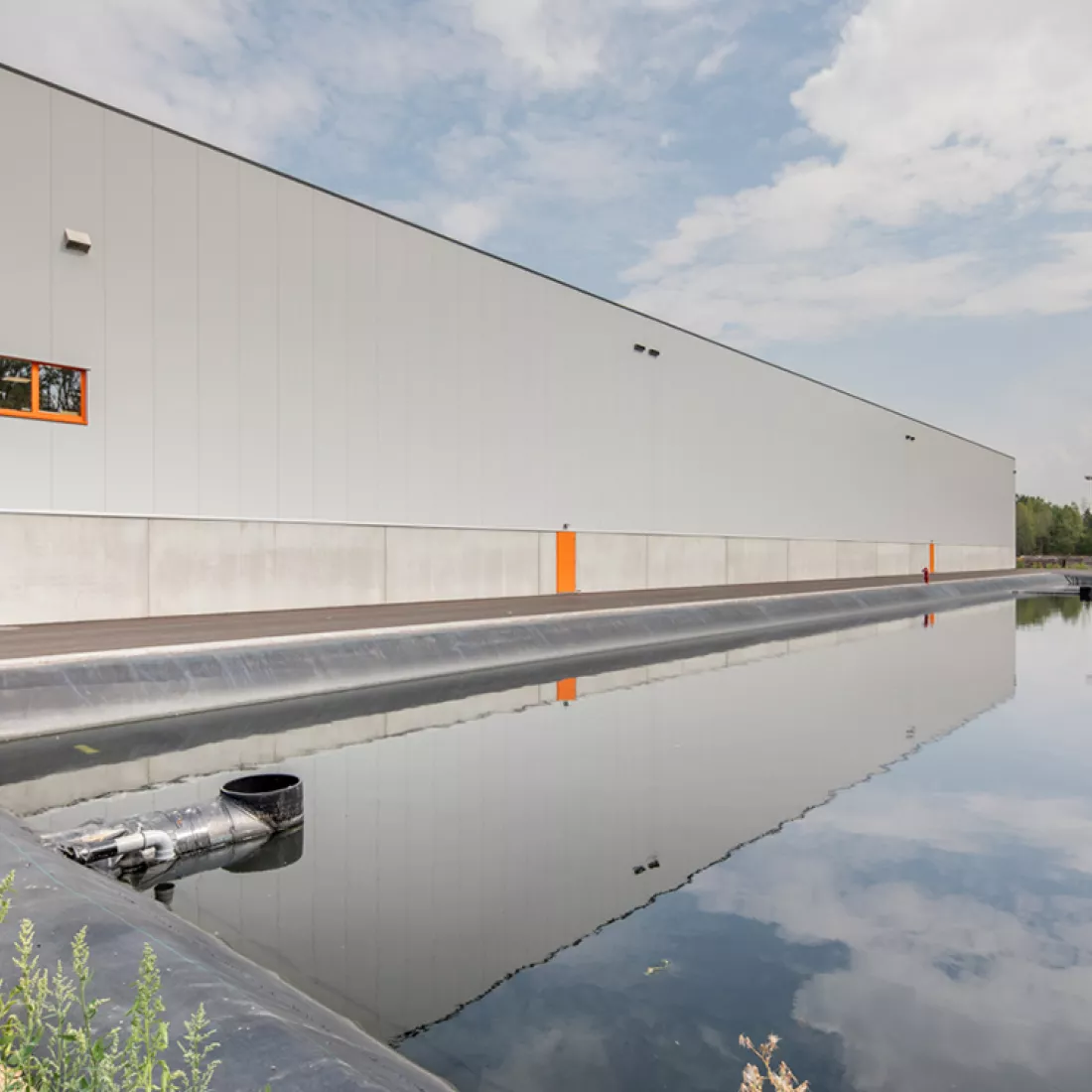 Achterkant magazijn Promat hal 9. Grijs gebouw met oranje details.