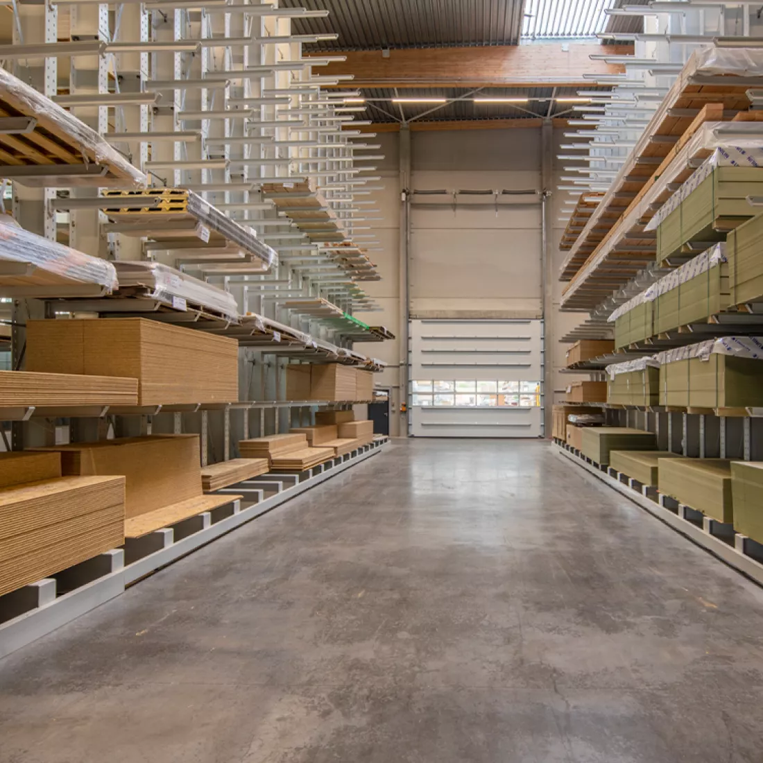Binnenkant stapel- en productiemagazijn Jofian. Achteraan bevindt zich een witte poort. Zowel links als rechts staan rekken met opgeslagen producten.