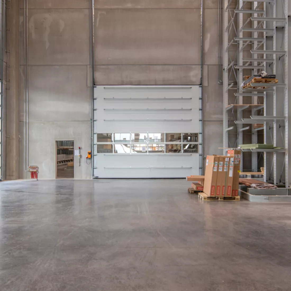 Close-up poort binnen in het stapel- en productiemagazijn van Jofian. Links naast de poort is een deur. Rechts staan rekken met opgeslagen producten.