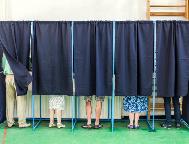 Kleurbeeld van - mensen die stemmen in stemcabines op een stembureau.
