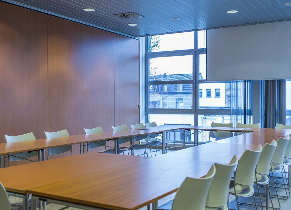 vergaderlokaal 2B zicht op tafels en stoelen met scherm