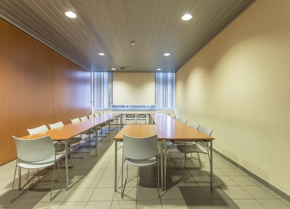 vergaderlokaal 2B zicht op tafels en stoelen met scherm