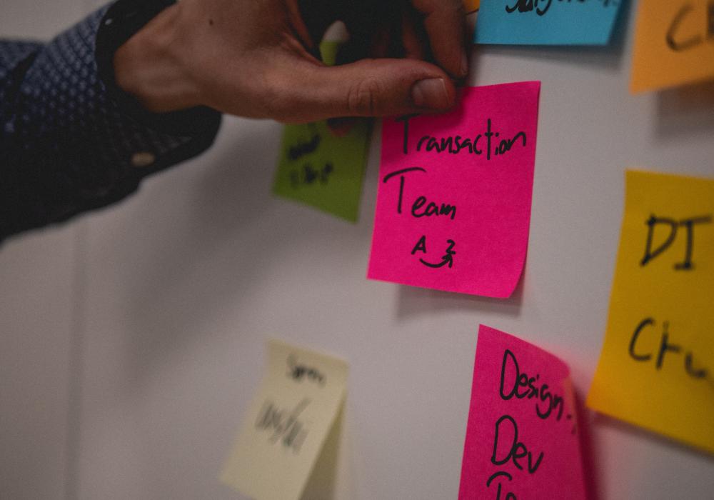 Post-its plakken op de muur voor een meeting - Unsplash
