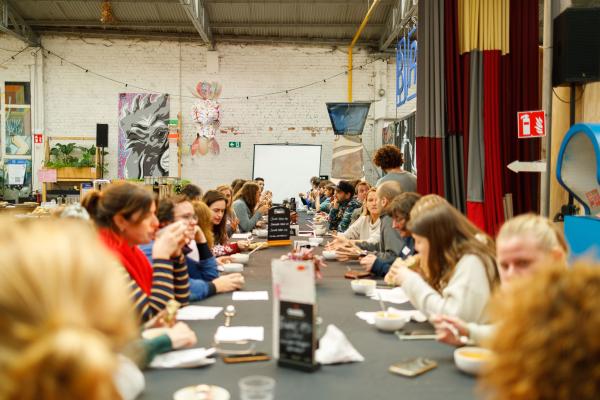 Jeugdwerkers aan het lunchen aan een lange tafel