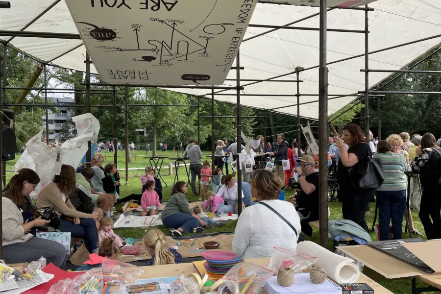 Grootouders, ouders en kinderen knutselen tijdens een in en uitloopworkshop tijdens een familiefestival
