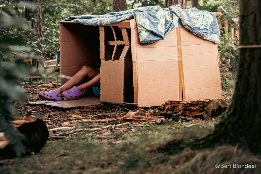 Geknutseld huis van karton met voeten van kind eruit in een ontspannen vrije tijd setting in het bos