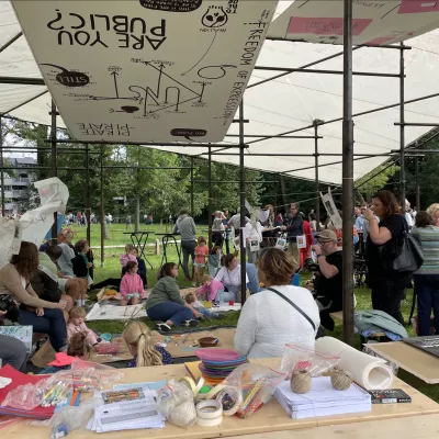 Grootouders, ouders en kinderen knutselen tijdens een in en uitloopworkshop tijdens een familiefestival