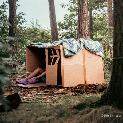 Geknutseld huis van karton met voeten van kind eruit in een ontspannen vrije tijd setting in het bos