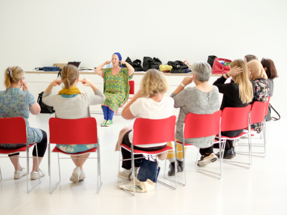 Een groep mensen die onder leiding van een begeleider bepaalde bewegingen uitoefenen.