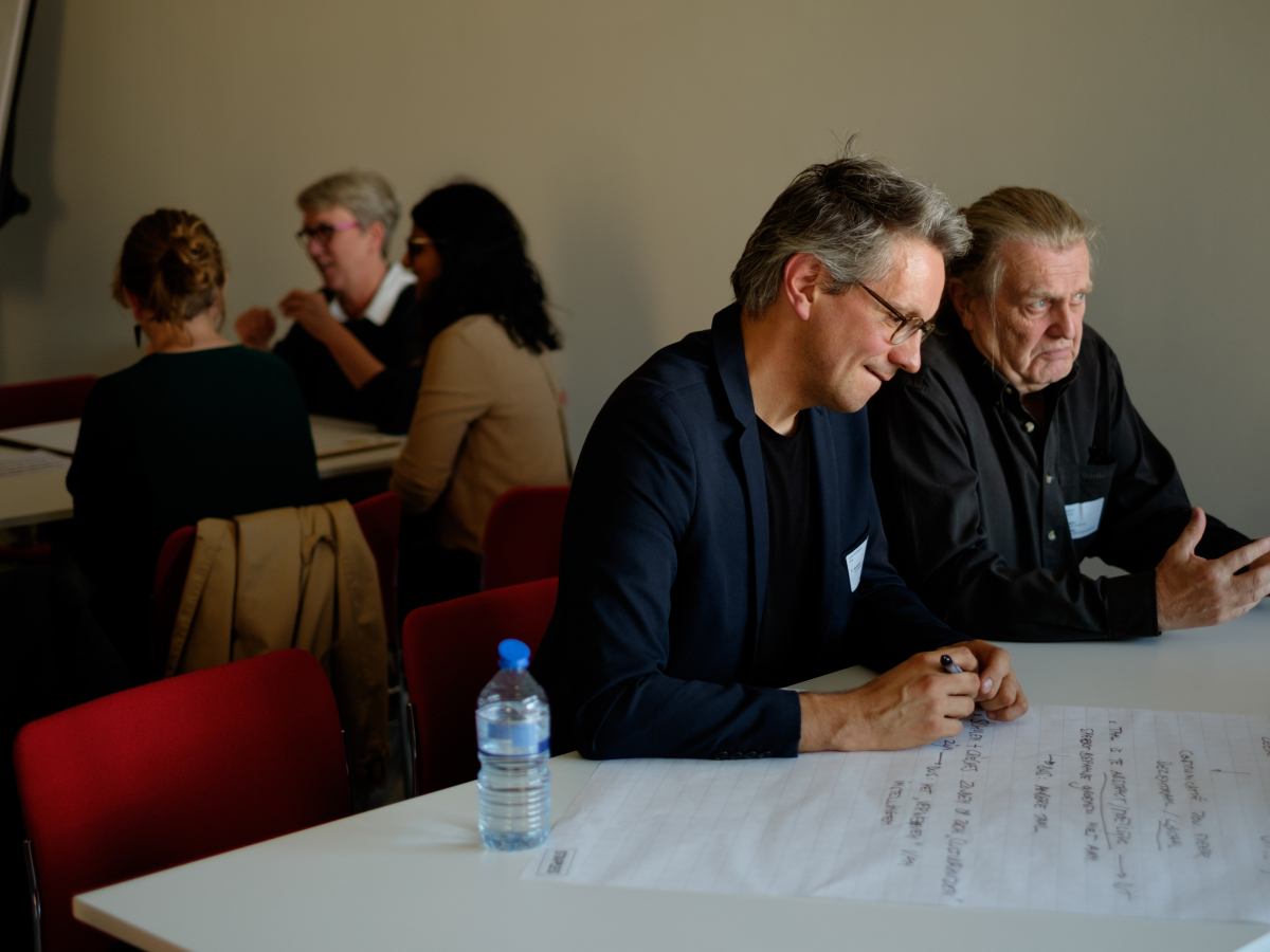 Twee mannen aan een tafel die brainstormen.