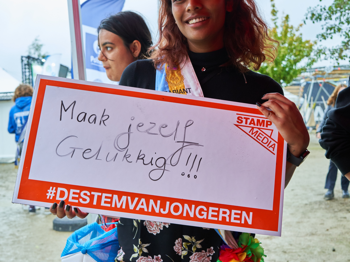 Jongere met bordje vast met 'maak jezelf gelukkig' op
