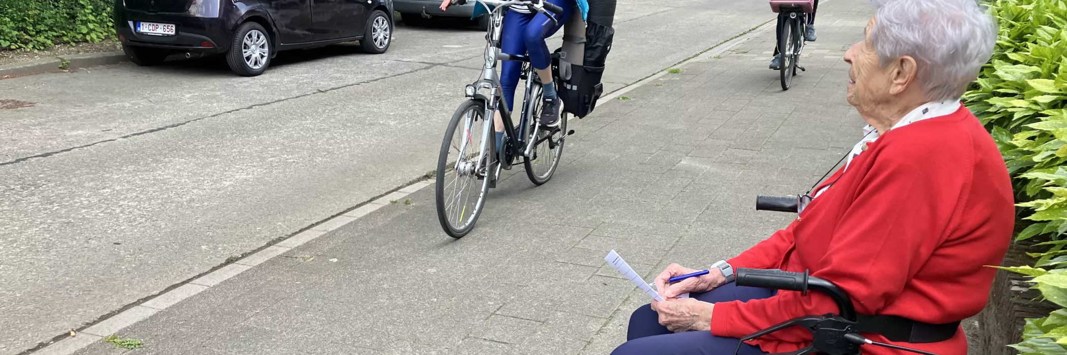Een vrouw zittend op een rollator telt het verkeer op straat
