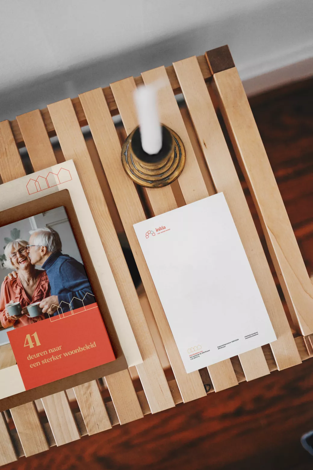 foto van briefpapier en brochure van Initia, liggend op een houten tafeltje met kaars