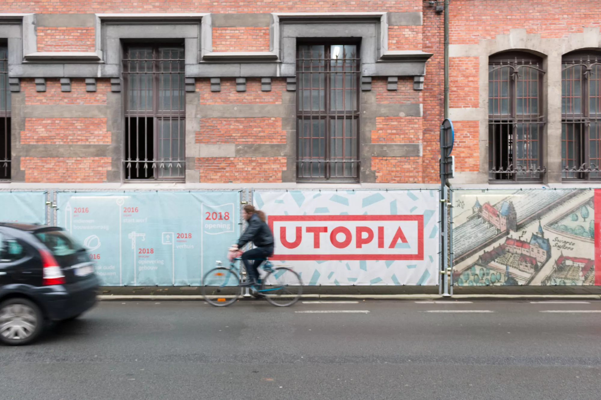 logo van utopia aan werfdoek terwijl fietser voorbijrijdt