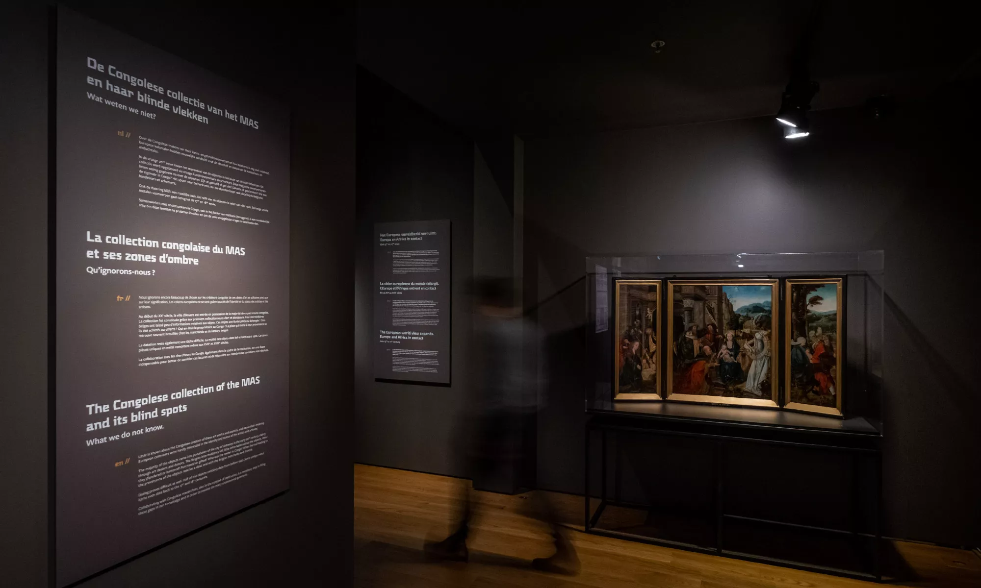 beeld van donker museum met kunstwerk en begeleidende tekst